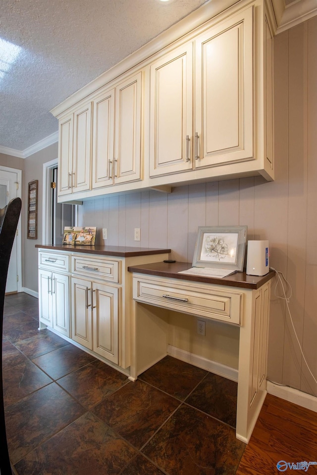 kitchen with cream cabinets, crown molding, and a textured ceiling