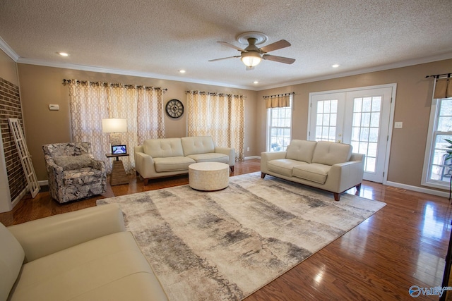 living room with wood-type flooring, ceiling fan, crown molding, a textured ceiling, and french doors