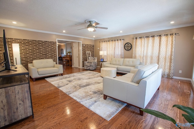 living room with a wood stove, hardwood / wood-style flooring, ceiling fan, crown molding, and a textured ceiling