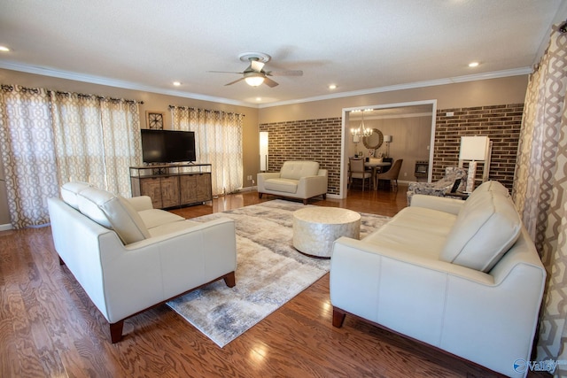 living room with crown molding, brick wall, dark hardwood / wood-style floors, and ceiling fan with notable chandelier