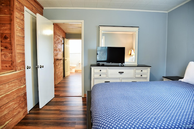 bedroom with crown molding, wood walls, and dark hardwood / wood-style floors