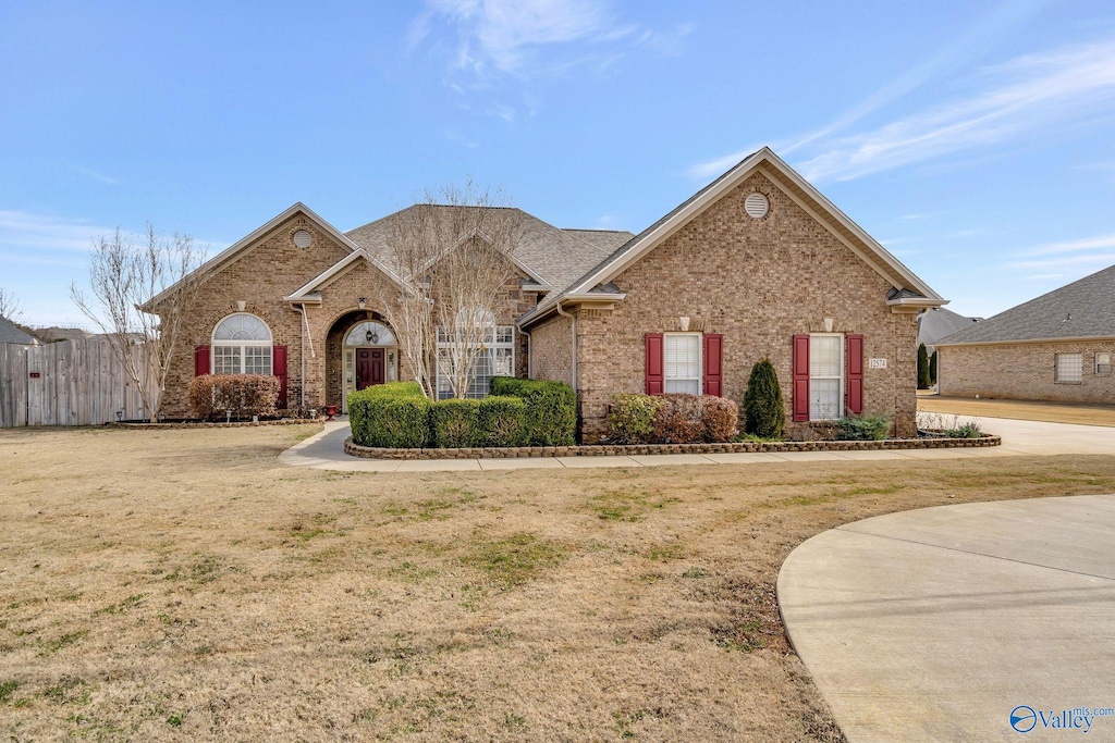 view of front of home with brick siding, fence, and a front lawn