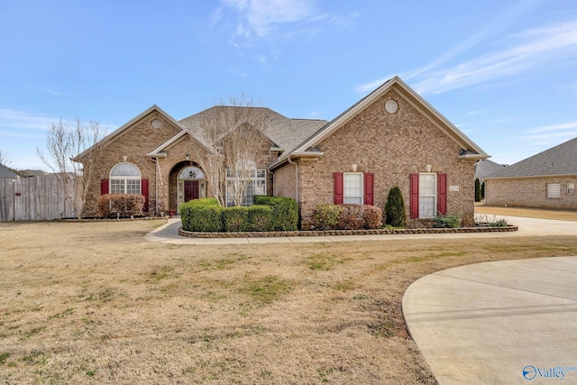 view of front of home with brick siding, fence, and a front lawn