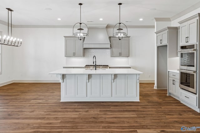 kitchen with tasteful backsplash, premium range hood, gray cabinetry, and decorative light fixtures