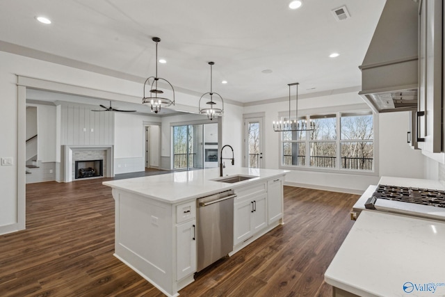 kitchen featuring dark wood-type flooring, white cabinetry, hanging light fixtures, a center island with sink, and dishwasher