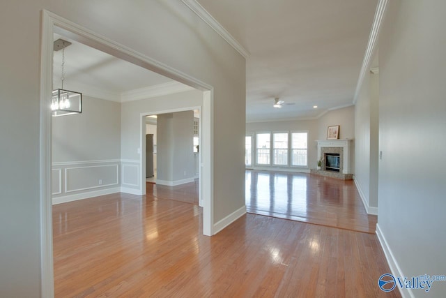 spare room with light wood-type flooring, ceiling fan with notable chandelier, and crown molding