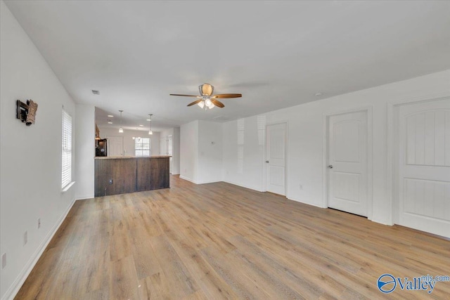 unfurnished living room featuring a ceiling fan and light wood finished floors