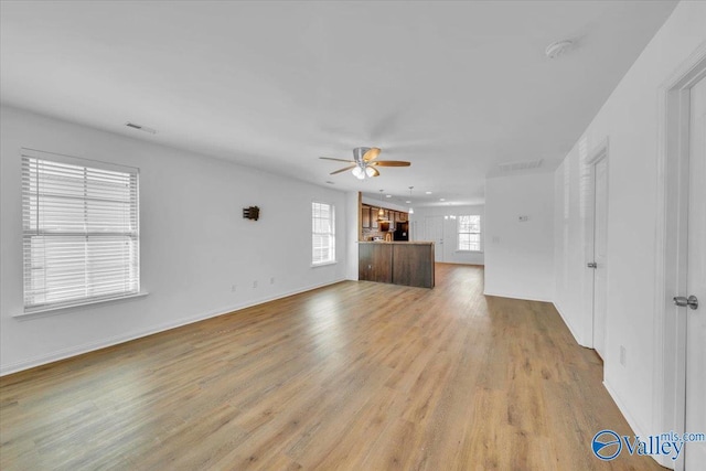 unfurnished living room featuring baseboards, a ceiling fan, visible vents, and light wood-type flooring