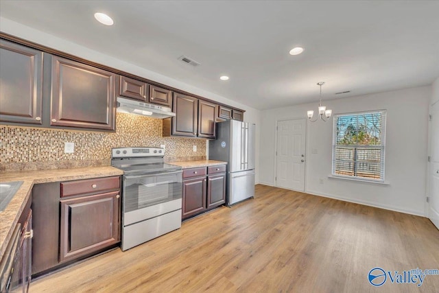 kitchen featuring under cabinet range hood, a notable chandelier, appliances with stainless steel finishes, and light wood finished floors