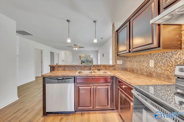 kitchen featuring visible vents, under cabinet range hood, a sink, stainless steel appliances, and a peninsula