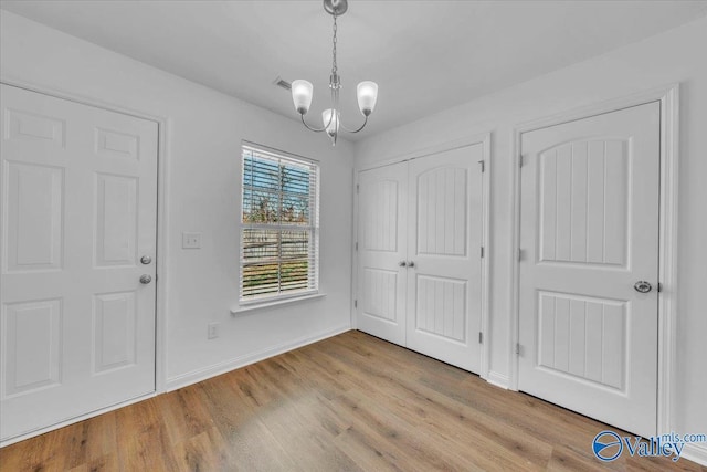 entrance foyer featuring a chandelier, visible vents, baseboards, and wood finished floors