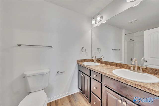 bathroom with visible vents, toilet, wood finished floors, and a sink