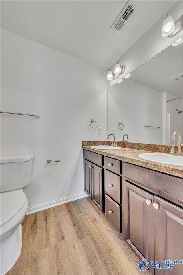 bathroom featuring a sink, visible vents, toilet, and wood finished floors