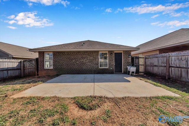 back of property with brick siding, a fenced backyard, and a patio