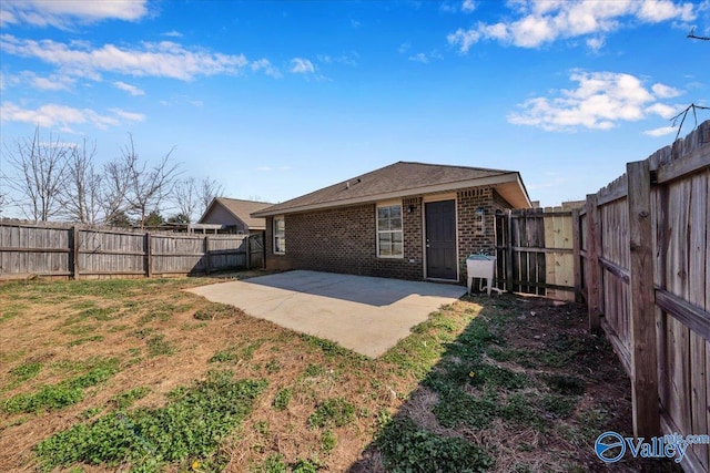 back of house featuring a lawn, a sink, a fenced backyard, brick siding, and a patio area