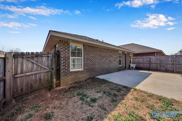 back of property with a patio, a fenced backyard, and brick siding