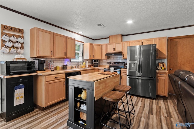 216 Mcdonald Ln, Guntersville, AL 35976 - kitchen with black appliances, under cabinet range hood, light wood finished floors, ornamental molding, and backsplash