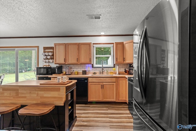 216 Mcdonald Ln, Guntersville, AL 35976 - kitchen featuring black appliances, a textured ceiling, light wood-style floors, plenty of natural light, and tasteful backsplash