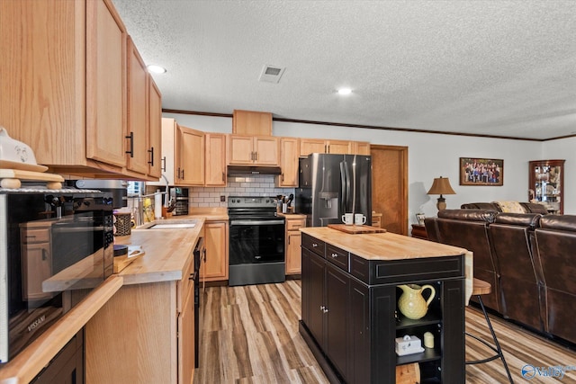 216 Mcdonald Ln, Guntersville, AL 35976 - kitchen with wood counters, appliances with stainless steel finishes, under cabinet range hood, light brown cabinets, and light wood-type flooring