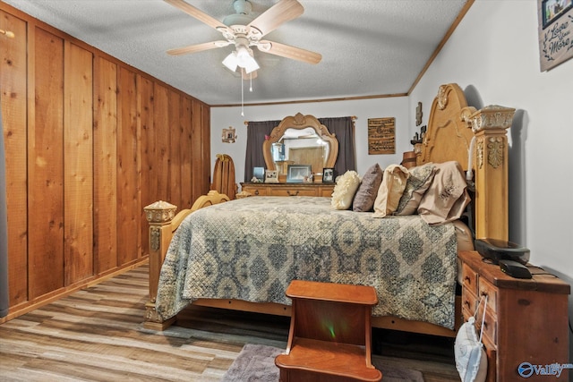 216 Mcdonald Ln, Guntersville, AL 35976 - bedroom with wood finished floors, a textured ceiling, ornamental molding, wooden walls, and a ceiling fan