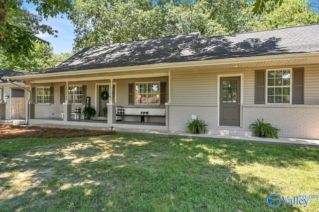 ranch-style home featuring brick siding, covered porch, and a front yard