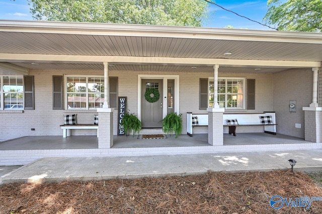doorway to property with brick siding and a porch