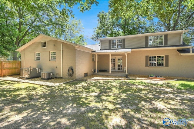 rear view of property featuring central air condition unit, brick siding, fence, and french doors