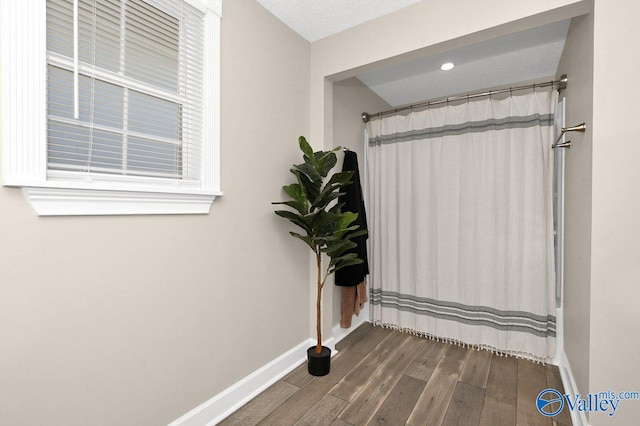 interior space with curtained shower, baseboards, and wood finished floors