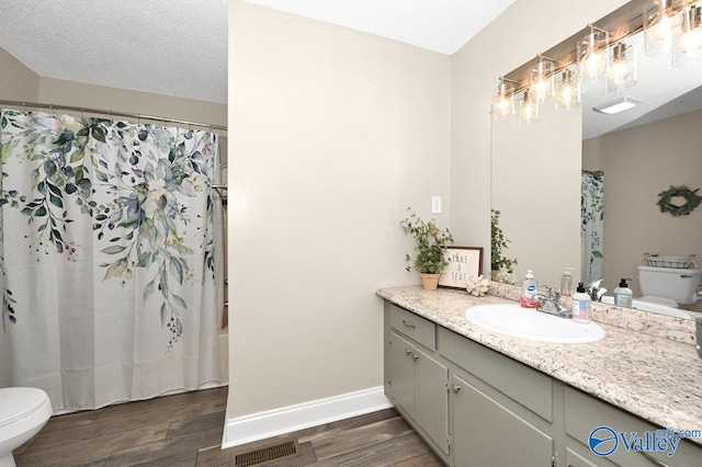 bathroom with toilet, wood finished floors, baseboards, and visible vents