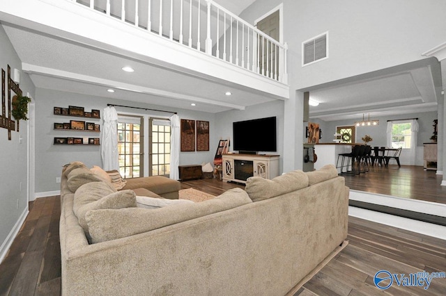 living room with recessed lighting, wood-type flooring, baseboards, a towering ceiling, and visible vents