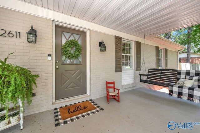 property entrance with brick siding and a porch