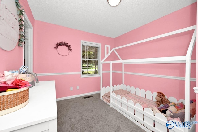 carpeted bedroom featuring baseboards, visible vents, and a textured ceiling