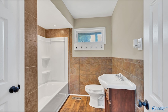 full bath with toilet, tile walls, visible vents, and vanity
