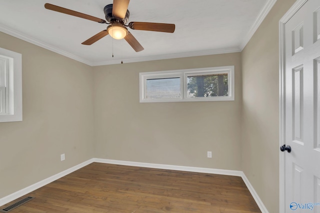 spare room featuring crown molding, baseboards, wood finished floors, and visible vents