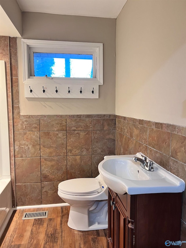 bathroom with tile walls, wood-type flooring, vanity, and toilet