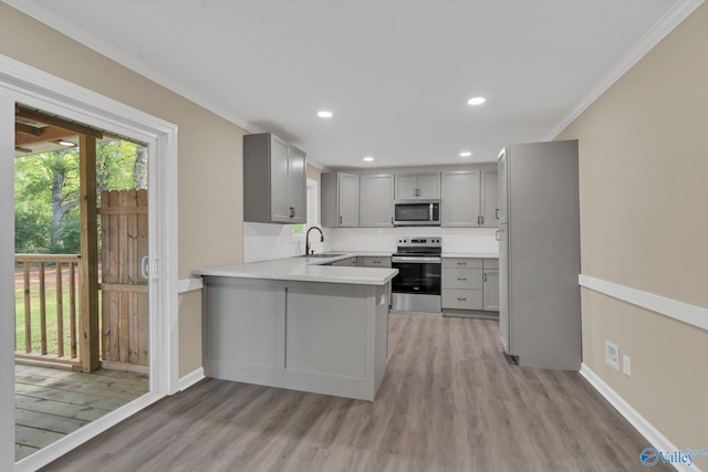 kitchen with gray cabinetry, appliances with stainless steel finishes, ornamental molding, and a sink