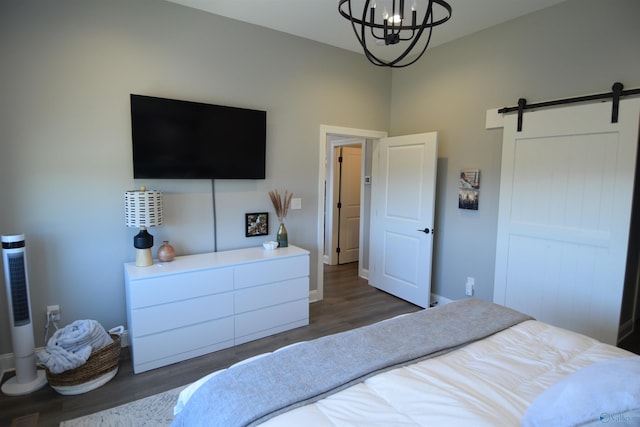 bedroom with dark wood-type flooring, a barn door, and an inviting chandelier