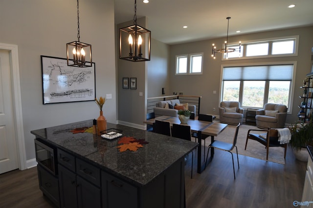 kitchen with a kitchen island, decorative light fixtures, dark hardwood / wood-style floors, and dark stone countertops