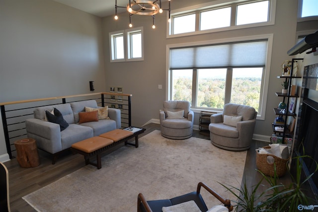 living room featuring a towering ceiling, a chandelier, wood-type flooring, and plenty of natural light