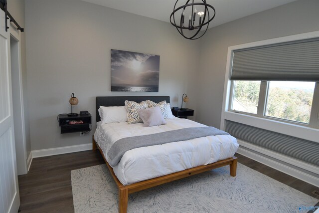 bedroom featuring a notable chandelier, a barn door, and dark hardwood / wood-style flooring