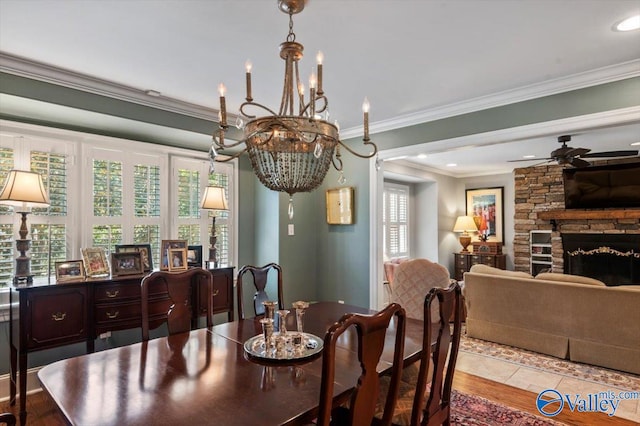 dining area featuring crown molding, ceiling fan with notable chandelier, light hardwood / wood-style flooring, and a fireplace