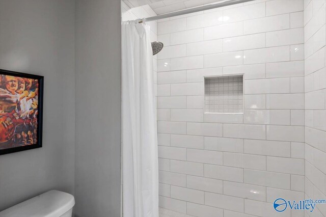 bathroom featuring toilet and tiled shower