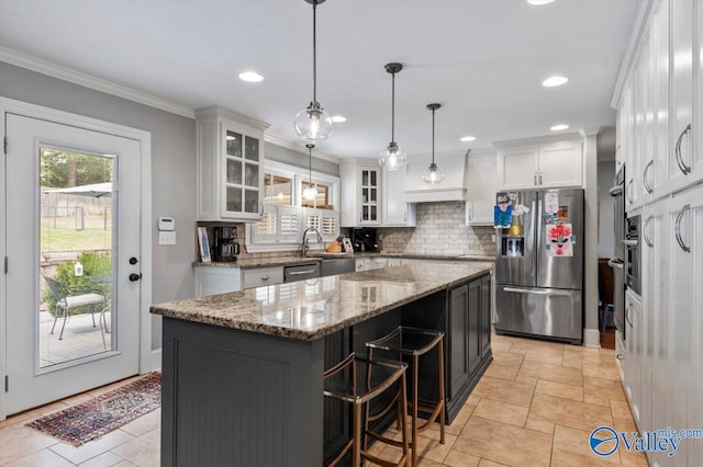 kitchen featuring appliances with stainless steel finishes, white cabinetry, a breakfast bar area, pendant lighting, and a kitchen island