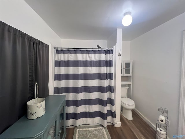 bathroom with curtained shower, hardwood / wood-style flooring, and toilet