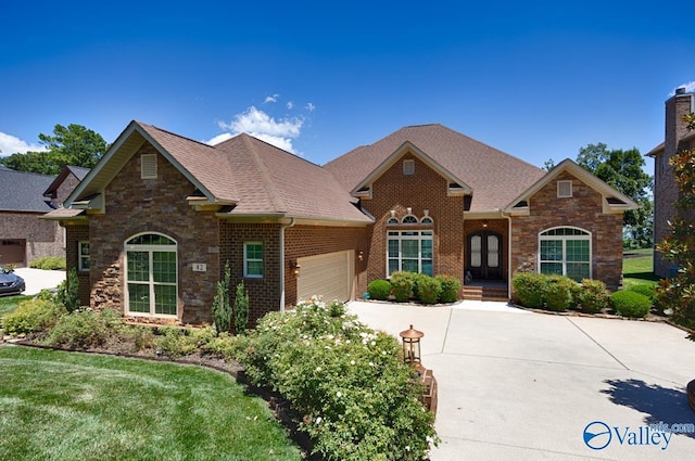 view of front of property featuring a garage, concrete driveway, brick siding, and roof with shingles