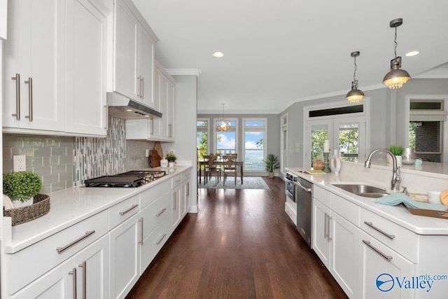 kitchen with under cabinet range hood, pendant lighting, stainless steel appliances, and light countertops