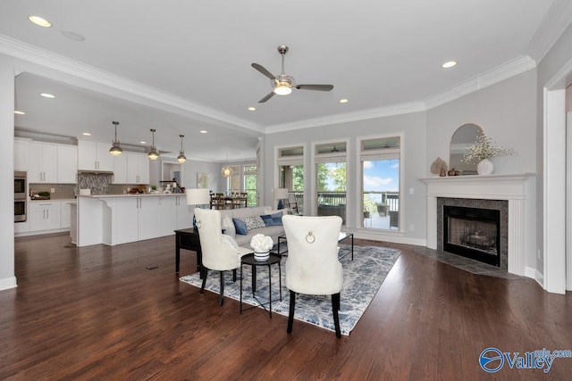 dining room featuring ornamental molding, dark wood-style flooring, a tile fireplace, and a ceiling fan