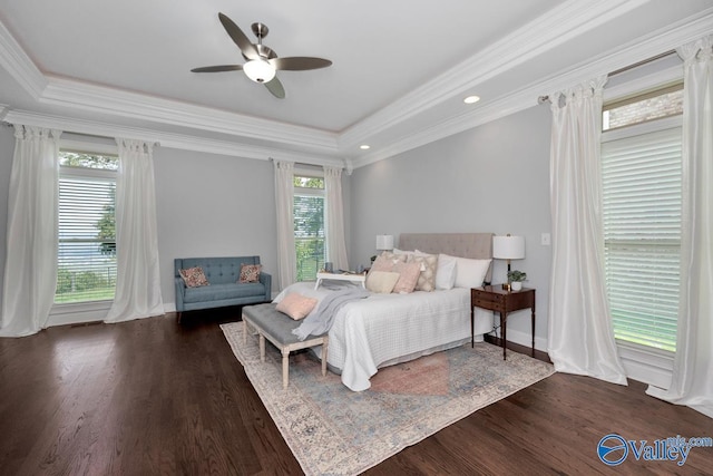 bedroom with crown molding, a tray ceiling, dark wood finished floors, and a ceiling fan