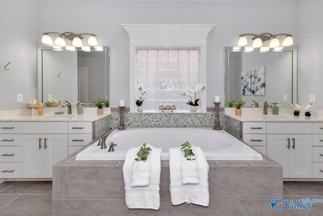 bathroom with a garden tub, tile patterned flooring, and a sink