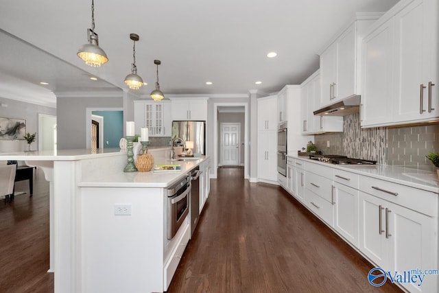 kitchen featuring decorative light fixtures, light countertops, under cabinet range hood, and white cabinetry